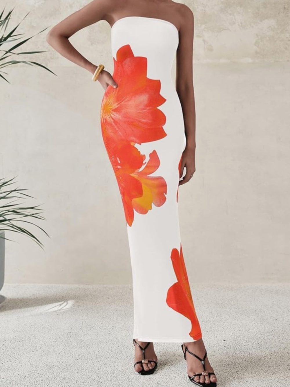 A sleek strapless maxi dress in white with a vibrant orange floral print. Smooth